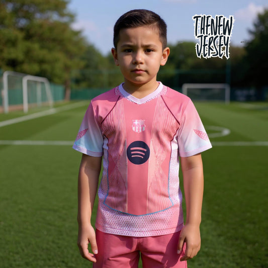 Child wearing pink Barcelona inspired kids football kit standing on a soccer field
