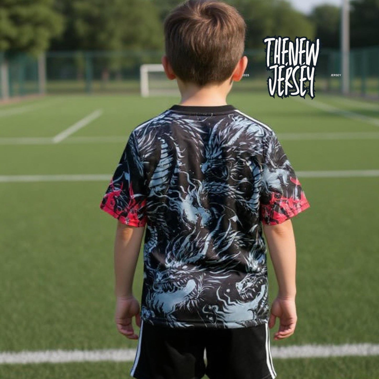 Back view of child wearing dark kids soccer kit with red details on football pitch
