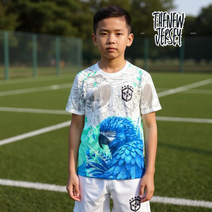 Child wearing Brazil inspired kids football kit in white and blue standing on a soccer field
